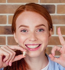 Woman holding extracted tooth making “ok” sign with her other hand