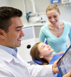 Dentist reviewing X-ray while patient waits in background