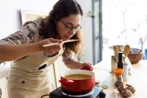 Woman cooking tasty soup in kitchen